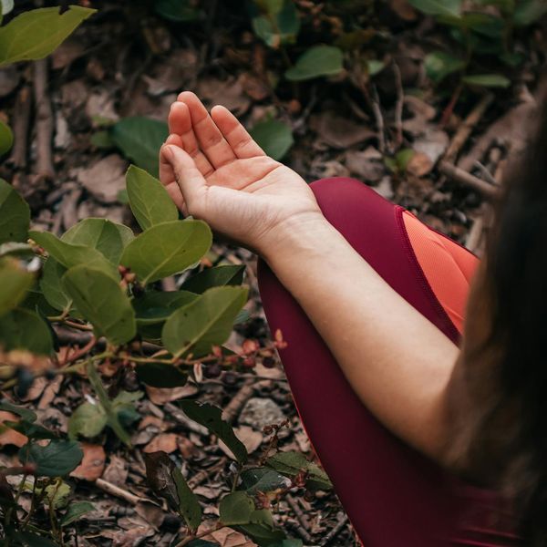 Person meditating peacefully outdoors surrounded by green nature.